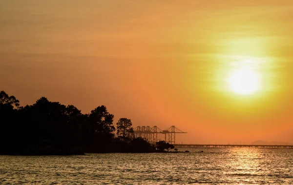 Napnyugtakor ég a tengeren a sziluett, a sziget és dock — Stock Fotó