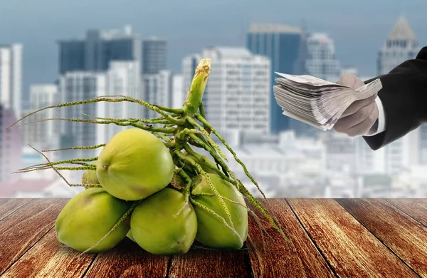 Uomo d'affari mano acquistare frutta di cocco con sfondo città — Foto Stock