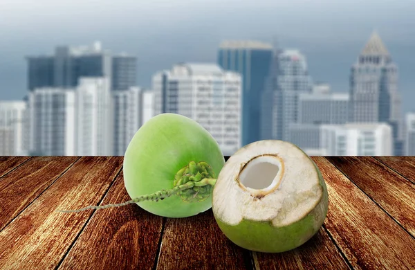 Fruta de coco no convés de madeira com vista para a cidade fundo — Fotografia de Stock