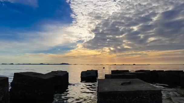 コンクリートブロック前景のシルエットを持つ海の夕日空の時間経過 — ストック動画