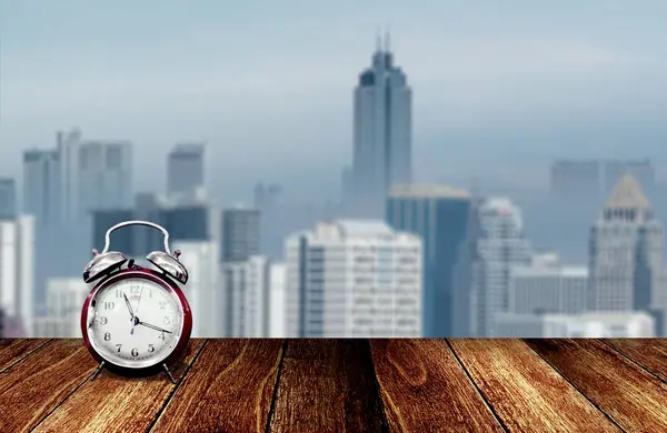 Alarm clock on wooden deck with ciytscape blurred background — Stock Photo, Image