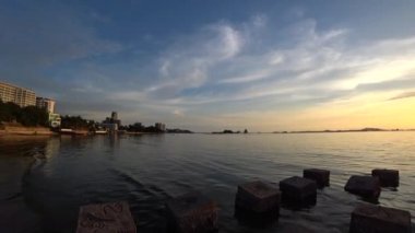 Denizde gün batımı gökyüzü beton blok ön planda, Panning çekim