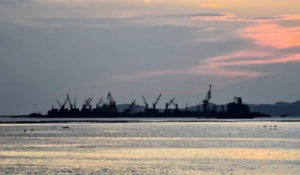 Silhouette eines kommerziellen Seehafens mit Inselhintergrund — Stockfoto