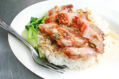 Beyaz tabakta pilavlı gevrek domuz eti.