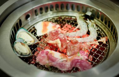 Barbekü ızgarasında taze et ve deniz ürünleri.