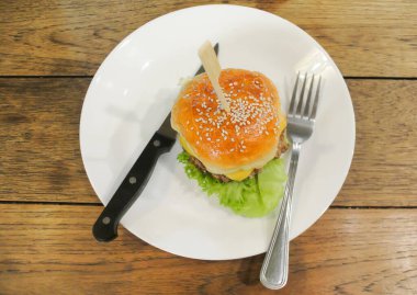 Yüksek açılı ahşap masada beyaz tabakta çizburger.