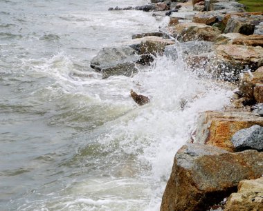 Sahilde kayalara çarpan deniz sörfü