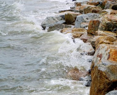 Sahilde kayalara çarpan deniz sörfü