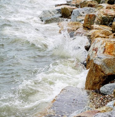 Sahilde kayalara çarpan deniz sörfü