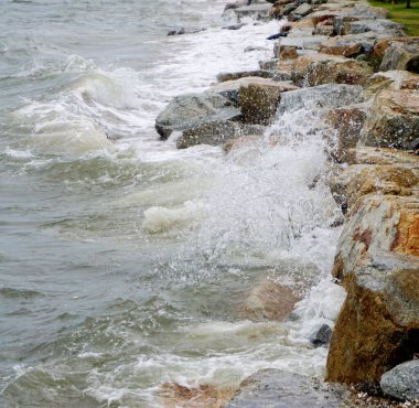 Sahilde kayalara çarpan deniz sörfü