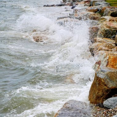 Sahilde kayalara çarpan deniz sörfü