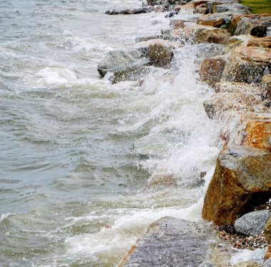 Sahilde kayalara çarpan deniz sörfü