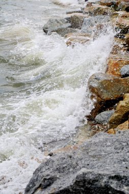 Sahilde kayalara çarpan deniz sörfü