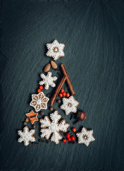 Pan de jengibre, nueces, especias, cáscara de naranja seca crean un árbol de Navidad sobre un fondo de piedra oscura —  Fotos de Stock