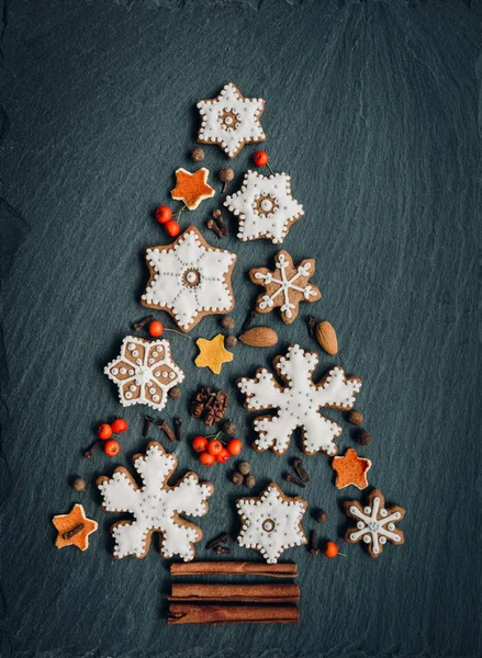 Pan de jengibre, nueces, especias, cáscara de naranja seca crean un árbol de Navidad sobre un fondo de piedra oscura — Foto de Stock