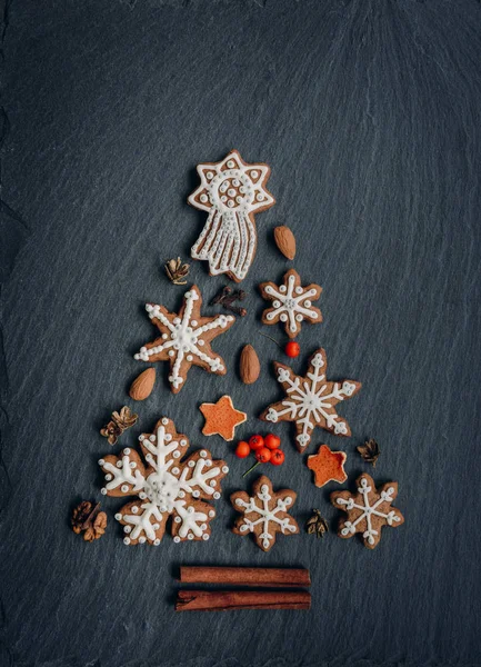 Pan de jengibre, nueces, especias, cáscara de naranja seca crean un árbol de Navidad sobre un fondo de piedra oscura —  Fotos de Stock