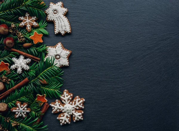 Cadre avec branches de sapin, biscuits et décorations de Noël sur fond de pierre sombre. Vue du dessus . — Photo