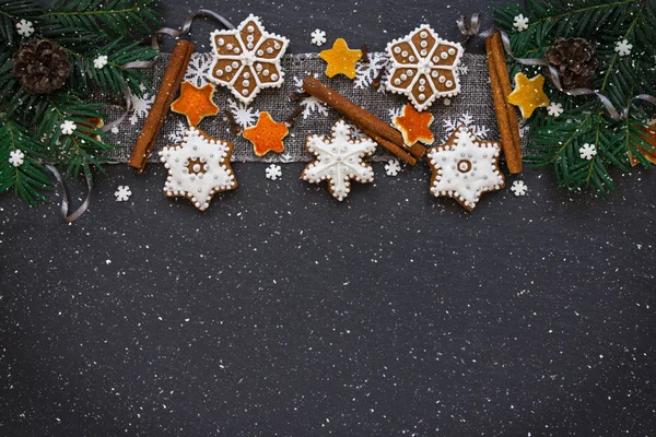 Cornice con rami di abete, biscotti e decorazioni natalizie su sfondo in pietra scura. Vista dall'alto . — Foto Stock
