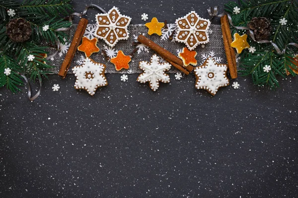 Marco con ramas de abeto, galletas y decoraciones navideñas sobre fondo de piedra oscura. Vista superior . — Foto de Stock