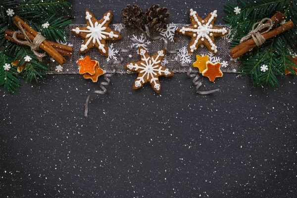 Keret, a fenyő ágak, a cookie-k és a karácsonyi díszek a sötét kő háttér. Szemközti nézet. — Stock Fotó