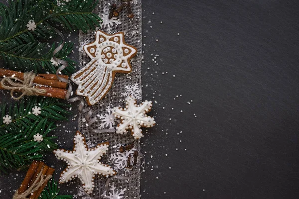 Moldura com ramos de abeto, biscoitos e decorações de Natal no fundo de pedra escura. Vista superior . — Fotografia de Stock