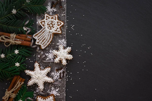 Moldura com ramos de abeto, biscoitos e decorações de Natal no fundo de pedra escura. Vista superior . — Fotografia de Stock