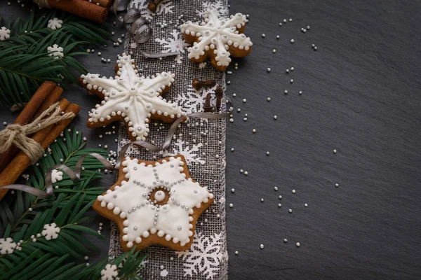 Marco con ramas de abeto, galletas y decoraciones navideñas sobre fondo de piedra oscura. Vista superior . —  Fotos de Stock