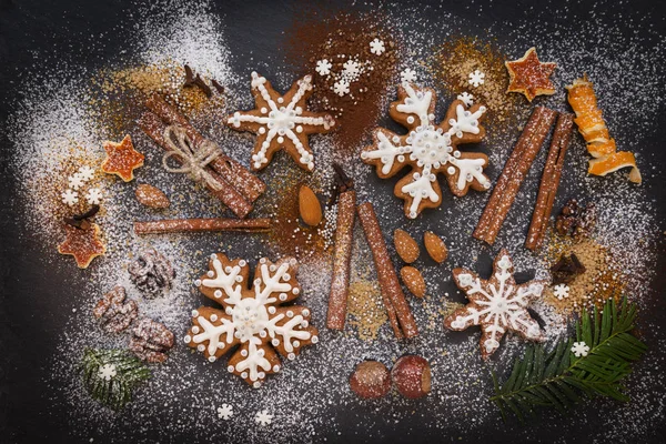 Kerstmis of Nieuwjaar achtergrond van Gingerbread koekjes, specerijen, noten met suiker en sneeuwvlokken. Bovenaanzicht. — Stockfoto