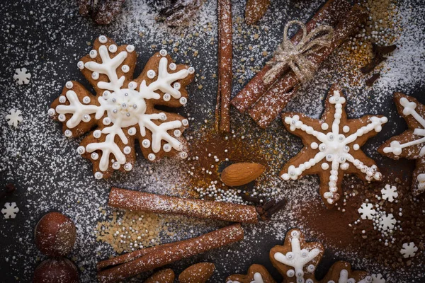 Kerstmis of Nieuwjaar achtergrond van Gingerbread koekjes, specerijen, noten met suiker en sneeuwvlokken. Bovenaanzicht. — Stockfoto