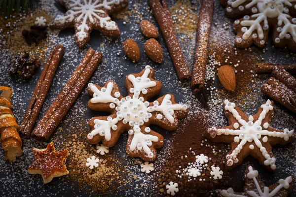 Kerstmis of Nieuwjaar achtergrond van Gingerbread koekjes, specerijen, noten met suiker en sneeuwvlokken. Bovenaanzicht. — Stockfoto