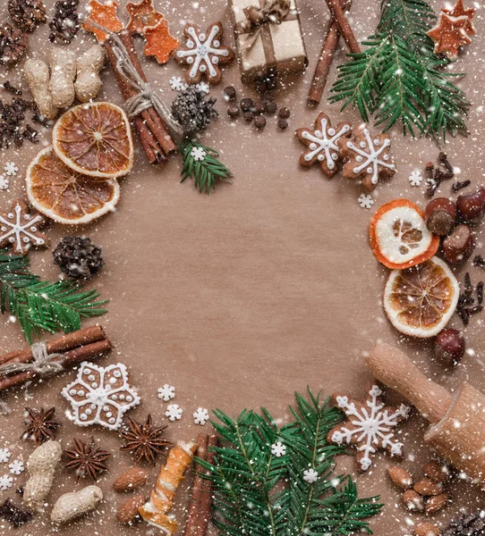 Marco con ramas de abeto, galletas y decoraciones navideñas sobre fondo de papel marrón oscuro. Vista superior . —  Fotos de Stock