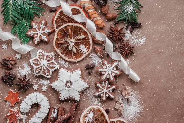 Cornice con rami di abete, biscotti e decorazioni natalizie su sfondo di carta marrone scuro. Vista dall'alto . — Foto Stock