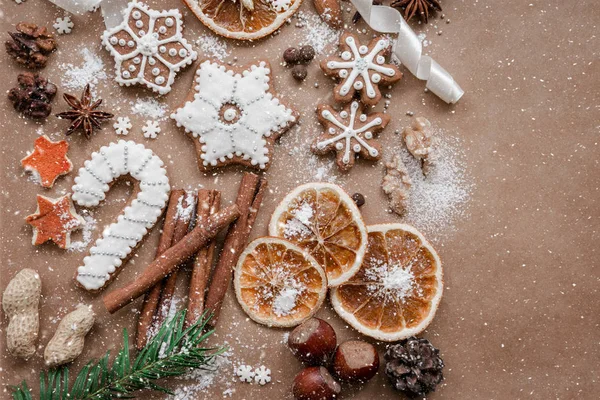 Çerçeve çam dalları, kurabiye ve koyu kahverengi kağıt arka plan üzerinde Noel süslemeleri ile. Üstten görünüm. — Stok fotoğraf