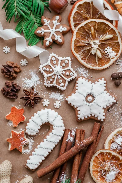 Cornice con rami di abete, biscotti e decorazioni natalizie su sfondo di carta marrone scuro. Vista dall'alto . — Foto Stock