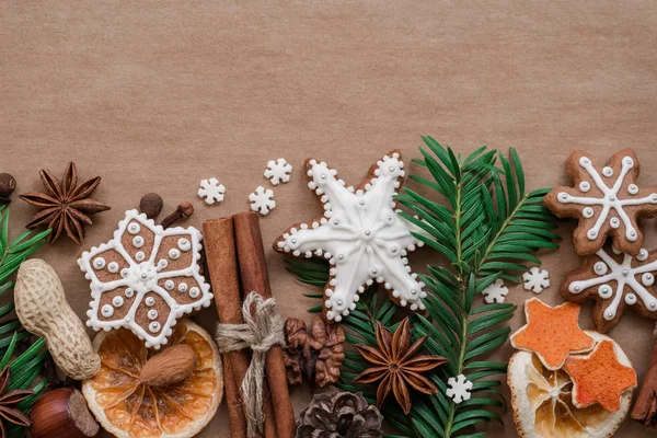 Cornice con rami di abete, biscotti e decorazioni natalizie su sfondo di carta marrone scuro. Vista dall'alto . — Foto Stock