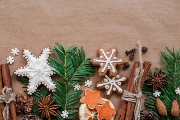 Frame met spar takken, cookies en kerstversiering op achtergrond donker bruin papier. Bovenaanzicht. — Stockfoto