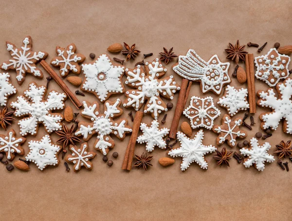 Dekorasi Natal dengan rempah-rempah dan kue dalam bentuk kepingan salju di latar belakang kertas cokelat gelap. Tampilan atas . — Stok Foto