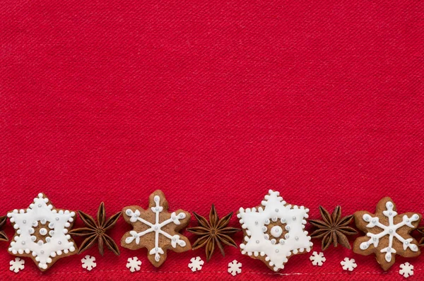 Decorazione natalizia su sfondo di tessuto rosso. Biscotti di Natale a forma di fiocchi di neve fatti a mano — Foto Stock