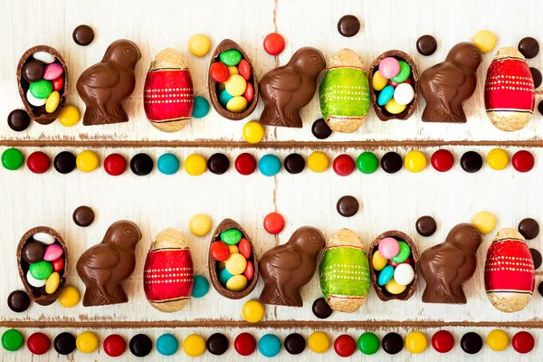 Sfondo pasquale con caramelle al cioccolato a forma di coniglio, pollo, uova e dolci — Foto Stock