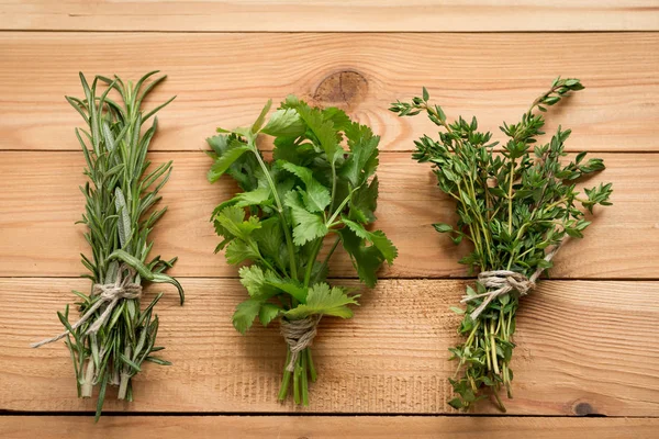 Bunch of rosemary, coriander and thyme, organic plants for healthy food. Wooden background