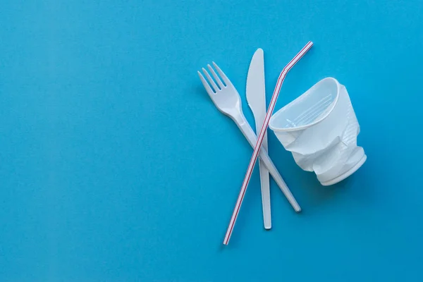 公害の象徴として青色の背景に白色のプラスチック単一の食器 単一の使用のプラスチックにノーと言う — ストック写真