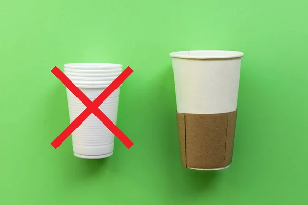 White single-use plastic and paper cup on a green background.
