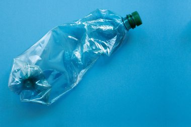 Ezilmiş ve mavi arka plana karşı buruşuk kullanılan plastik şişe