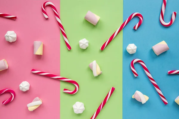 Alguns doces bengalas, marshmallows e merengues estão espalhados em papel colorido — Fotografia de Stock