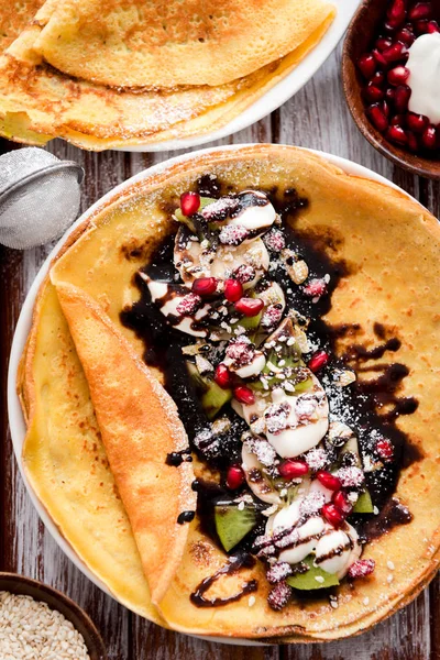 Thin Crepes with melted chocolate, sesame seeds, pomegranate and almonds — Stock Photo, Image