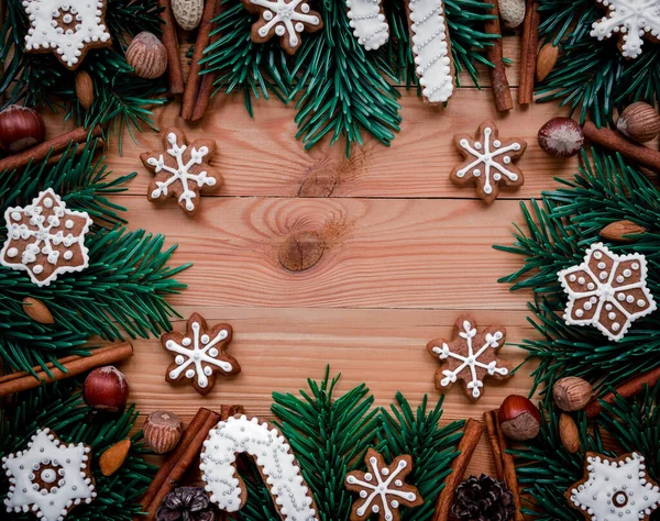 Cornice con rami di abete, biscotti e decorazioni natalizie su sfondo ligneo. Vista dall'alto . — Foto Stock