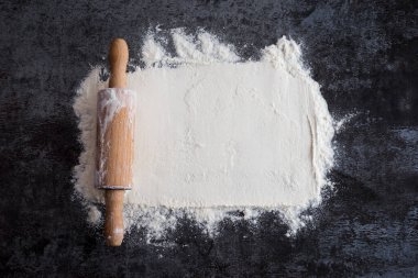 Koyu bir arka plan üzerinde oklava ve beyaz un