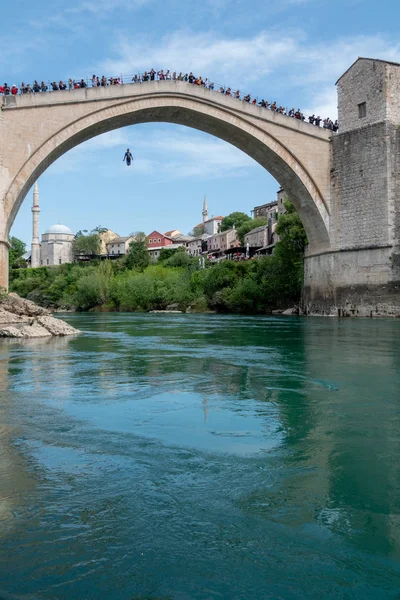 MOSTAR, BOSNIA-APRIL 21: Man jumping from old bridge on APRIL 21, 2019 in Mostar, Bosnia. По традиции мужчины ныряют с моста длиной 21 м. — стоковое фото