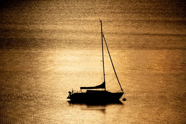 Silhuett av en segelbåt som flyter på en sjö — Stockfoto