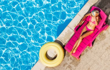 Yüzme havuzunun kenarında şezlong üzerinde ince genç kadının pembe bikini rahatlatıcı üstten görünüm